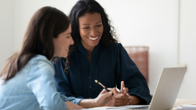 Woman speaking with her business mentor as business mentor looks at laptop